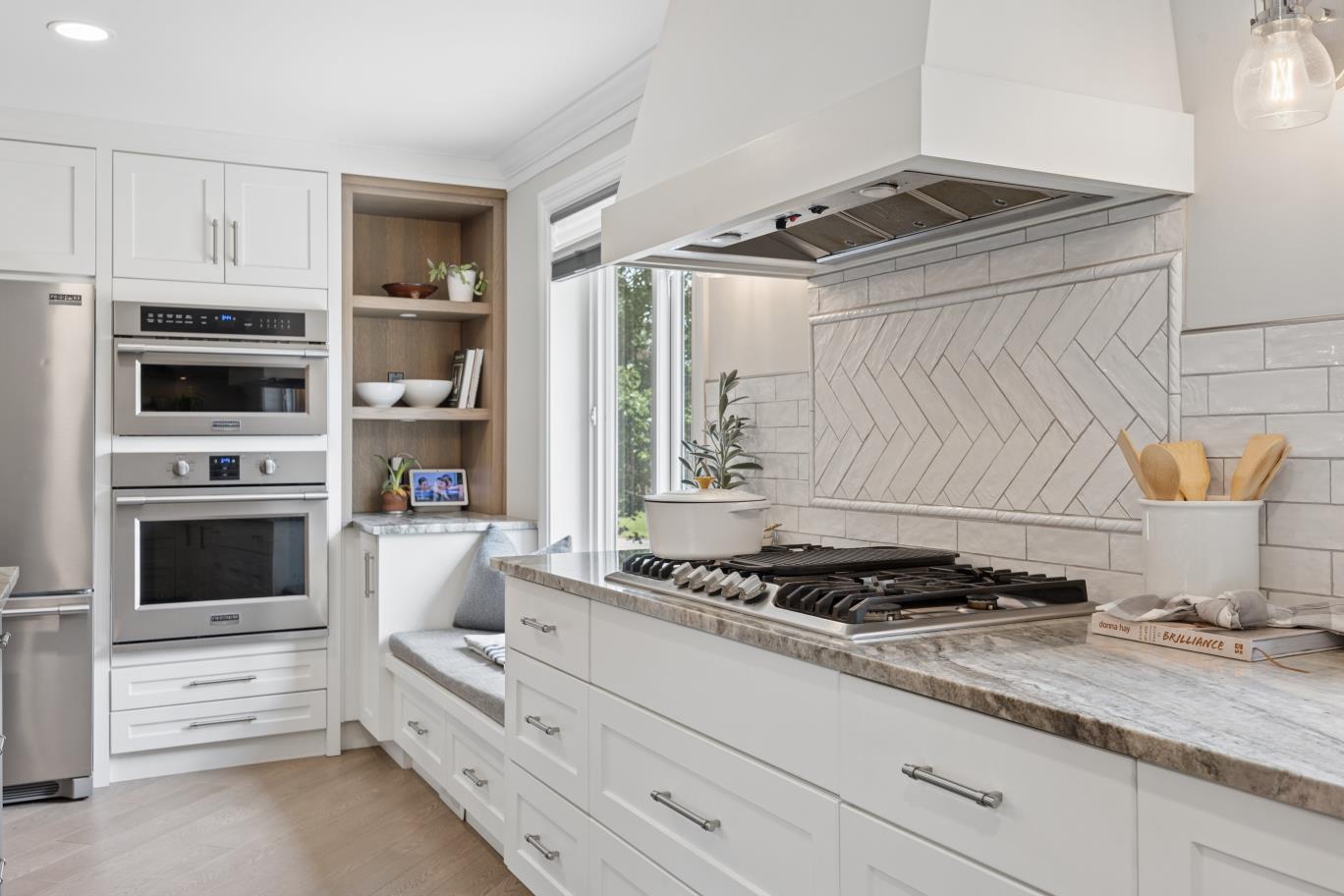 Gas range, herringbone backsplash, and built-in window bench in the 30 Potters Lane kitchen